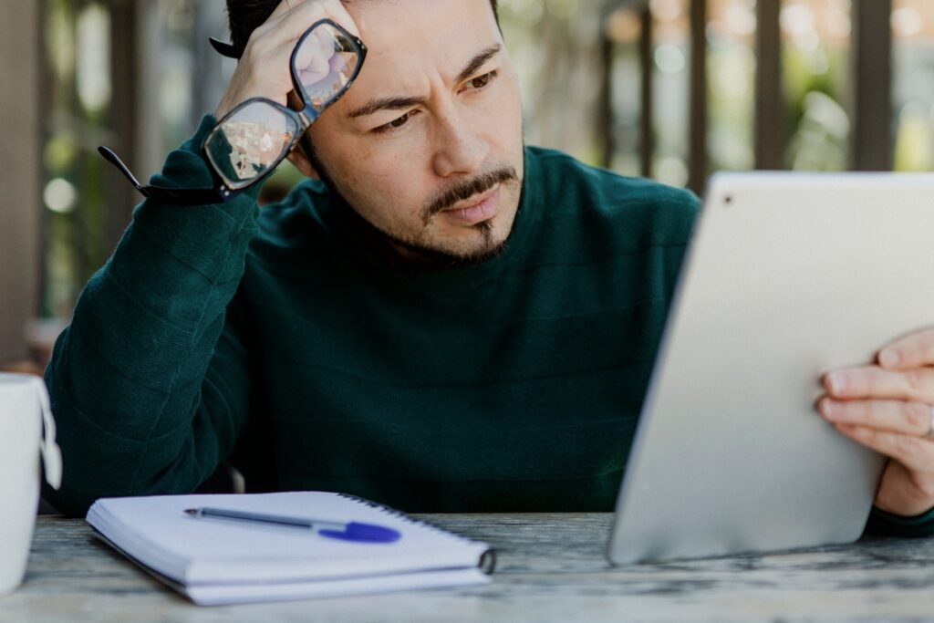 Un homme d'affaire, spécialiste du marketing digital, qui s'intérroge en regardant une tablette - AKIZIO